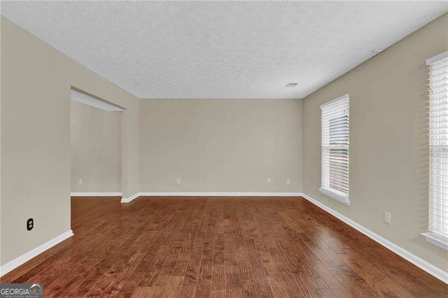 unfurnished room with wood finished floors, baseboards, and a textured ceiling