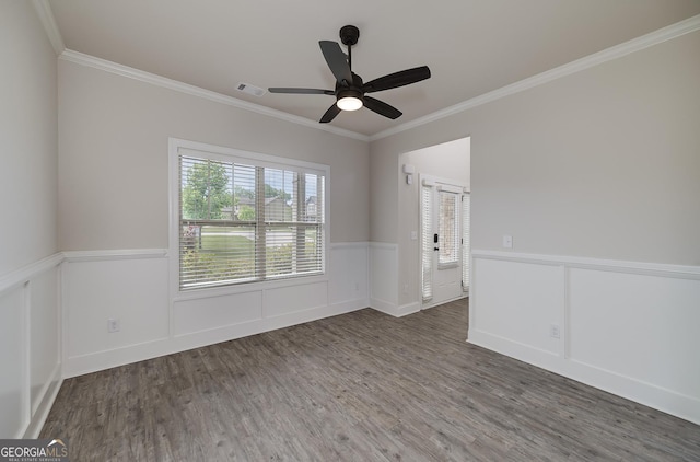 empty room with crown molding, a wainscoted wall, wood finished floors, and ceiling fan