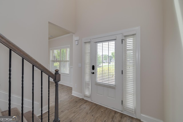 foyer entrance featuring wood finished floors, baseboards, stairs, and ornamental molding
