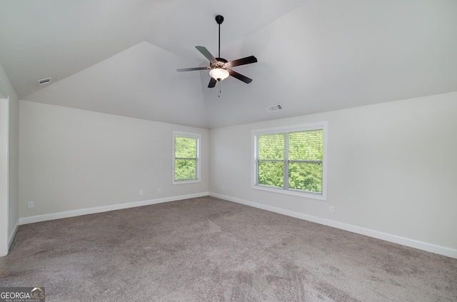 carpeted spare room with vaulted ceiling, a ceiling fan, and baseboards