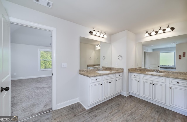 bathroom featuring two vanities, baseboards, and wood finished floors