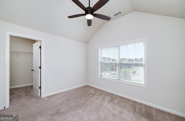 unfurnished bedroom featuring carpet, vaulted ceiling, a spacious closet, baseboards, and a closet