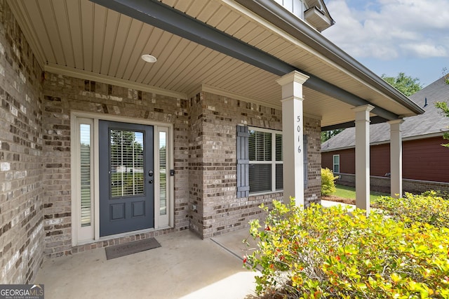 doorway to property with brick siding and covered porch