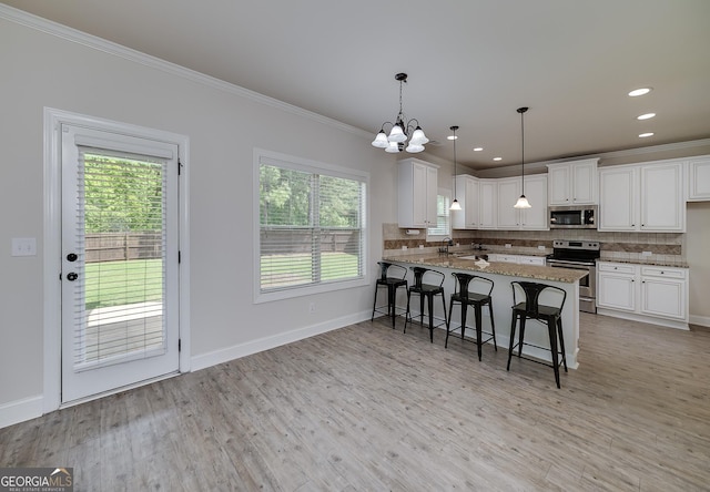 kitchen with stainless steel appliances, ornamental molding, a chandelier, backsplash, and white cabinetry