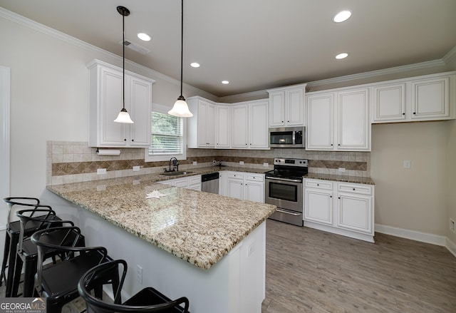 kitchen with stainless steel appliances, a sink, a peninsula, light wood-type flooring, and white cabinetry