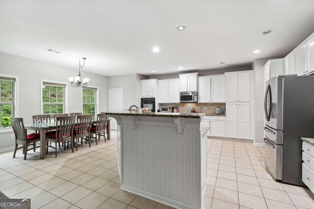 4960 Tadmore Ln, Lithonia, GA 30038 - kitchen featuring appliances with stainless steel finishes, light tile patterned floors, a kitchen bar, plenty of natural light, and recessed lighting