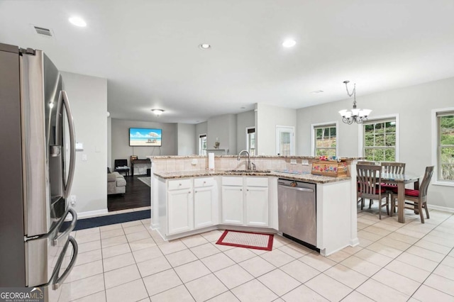 4960 Tadmore Ln, Lithonia, GA 30038 - kitchen with appliances with stainless steel finishes, a sink, a chandelier, white cabinetry, and light stone countertops
