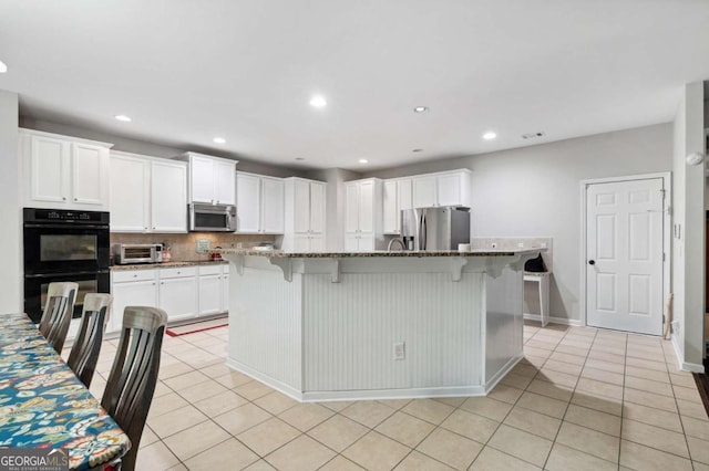 4960 Tadmore Ln, Lithonia, GA 30038 - kitchen with stainless steel appliances, a breakfast bar area, light tile patterned floors, white cabinetry, and recessed lighting