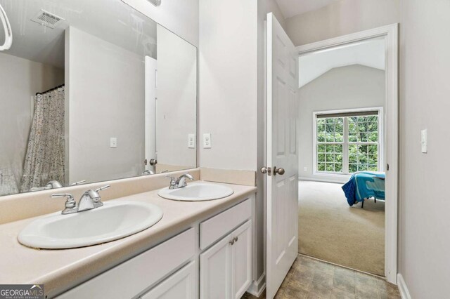 4960 Tadmore Ln, Lithonia, GA 30038 - bathroom featuring double vanity, baseboards, vaulted ceiling, and connected bathroom