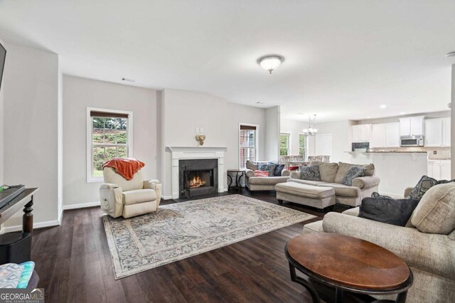 4960 Tadmore Ln, Lithonia, GA 30038 - living room featuring dark wood-style flooring, a chandelier, a fireplace with flush hearth, and baseboards