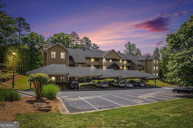 view of front of home with covered and uncovered parking and a lawn