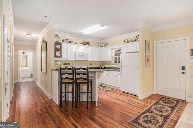 kitchen featuring white appliances, white cabinetry, a kitchen bar, light wood-type flooring, and ornamental molding