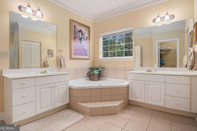 full bath featuring two vanities, ornamental molding, tile patterned floors, a garden tub, and a closet