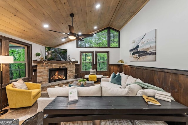 living area featuring wainscoting, ceiling fan, lofted ceiling, wooden ceiling, and a fireplace