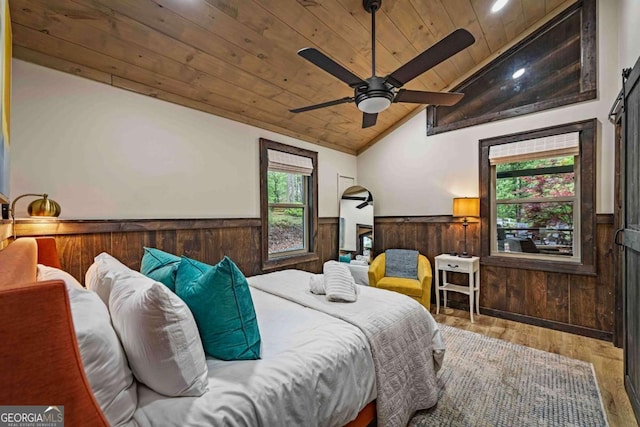 bedroom with wood ceiling, wainscoting, lofted ceiling, wood finished floors, and wood walls