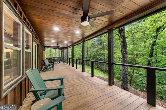 wooden terrace with ceiling fan and a view of trees