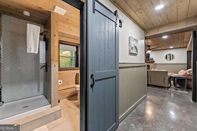 hall featuring wood ceiling, a barn door, wood walls, recessed lighting, and a wainscoted wall