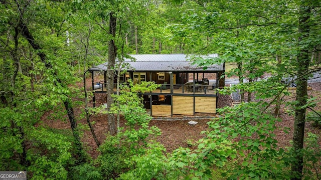 rear view of property featuring metal roof and a wooded view