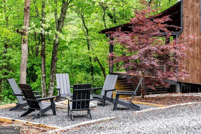 view of yard featuring an outdoor fire pit and a view of trees