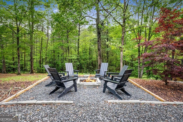 view of yard featuring an outdoor fire pit and a wooded view