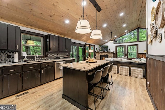 kitchen with a sink, dishwasher, a kitchen island, ceiling fan, and decorative backsplash