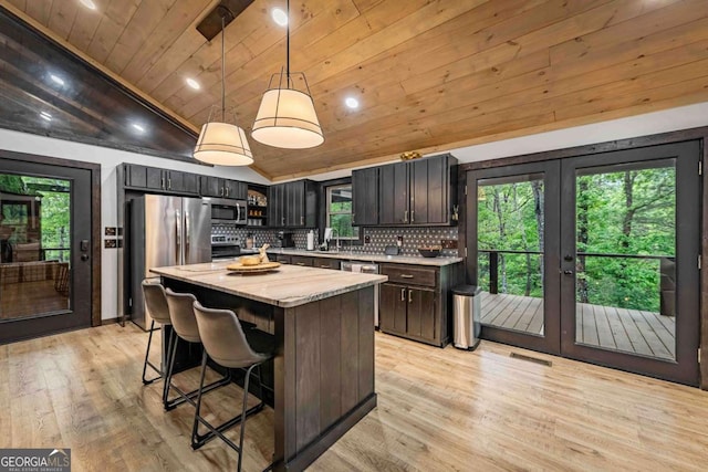 kitchen featuring french doors, lofted ceiling, wooden ceiling, stainless steel appliances, and tasteful backsplash