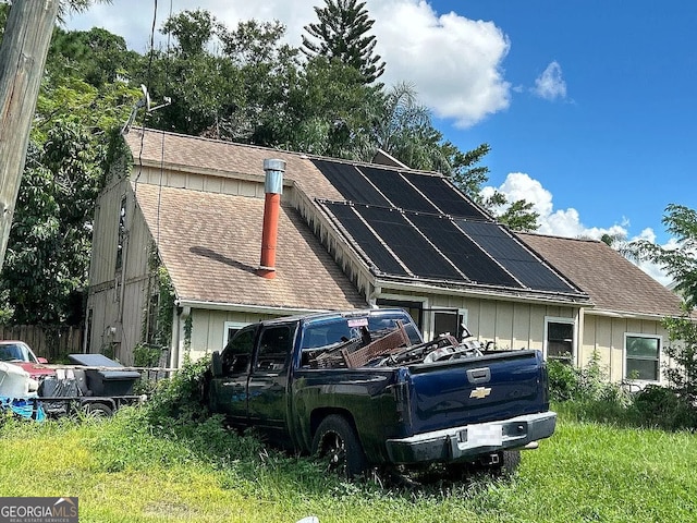 view of home's exterior with solar panels and roof with shingles
