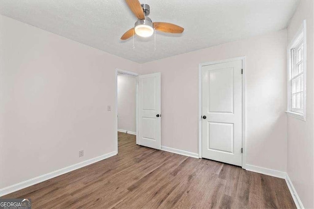 unfurnished bedroom with wood finished floors, baseboards, and a ceiling fan