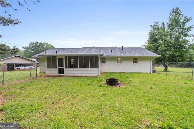 rear view of property with an outdoor fire pit, a sunroom, and roof with shingles