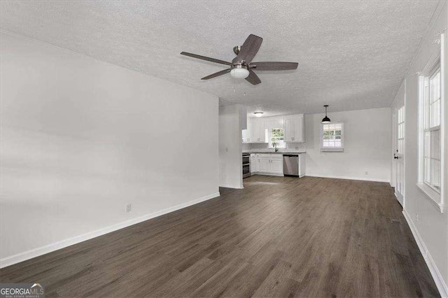 unfurnished living room featuring a textured ceiling, dark wood-style flooring, ceiling fan, baseboards, and a sink