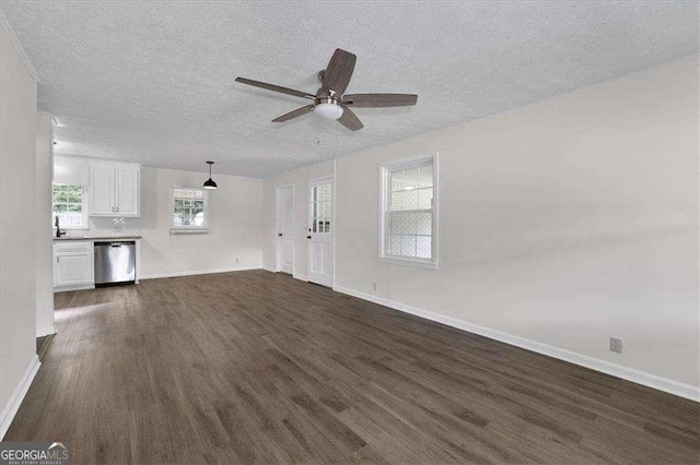 unfurnished living room featuring dark wood-type flooring, a textured ceiling, baseboards, a ceiling fan, and a sink