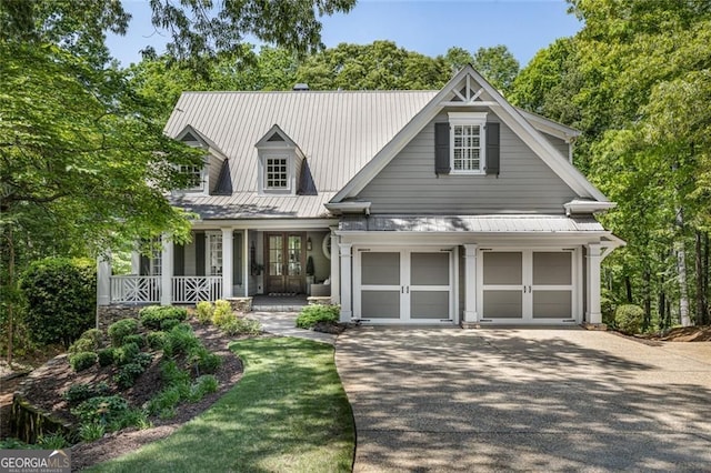 view of front of property with french doors, driveway, covered porch, and metal roof