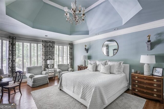 bedroom with a chandelier, crown molding, a tray ceiling, and wood finished floors