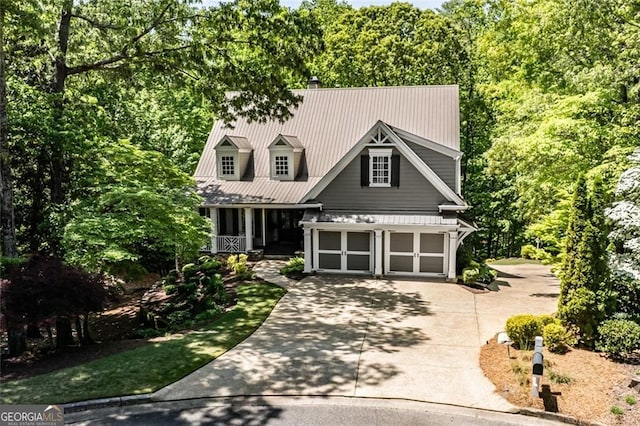 view of front of house featuring concrete driveway, metal roof, and a porch
