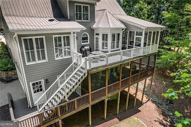 rear view of property with a sunroom, a deck, stairs, and metal roof