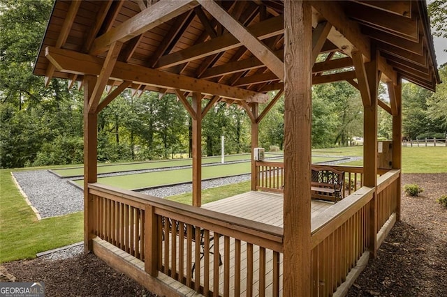 deck with a game area, view of scattered trees, and a lawn