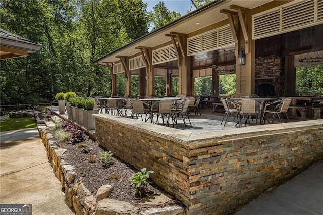 view of patio with an outdoor stone fireplace and outdoor dining area