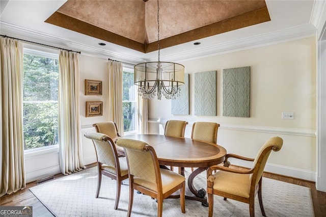 dining room with a tray ceiling, a chandelier, crown molding, and wood finished floors