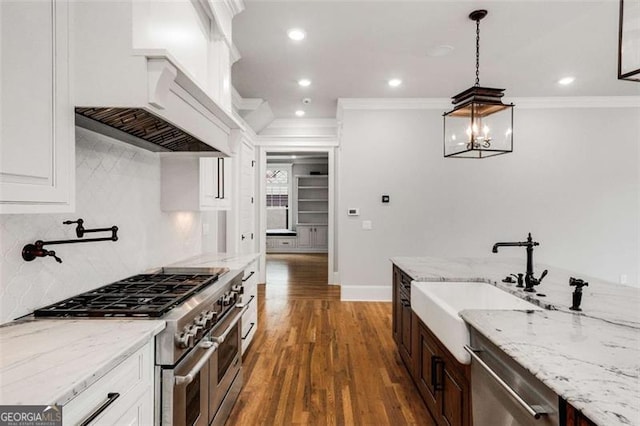 kitchen featuring stainless steel appliances, crown molding, a sink, wood finished floors, and recessed lighting