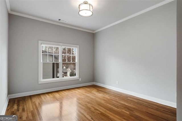 empty room featuring baseboards, wood finished floors, and crown molding