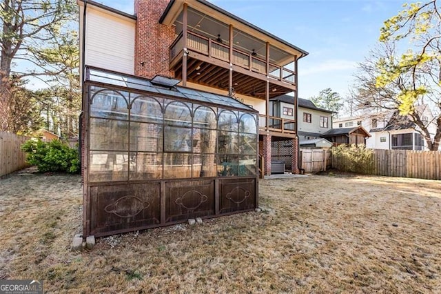 back of property with a fenced backyard, a wooden deck, a balcony, and a chimney