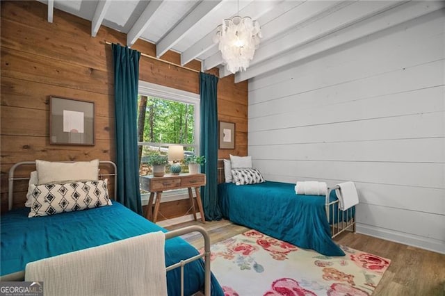 bedroom with beam ceiling, wooden walls, a chandelier, and wood finished floors