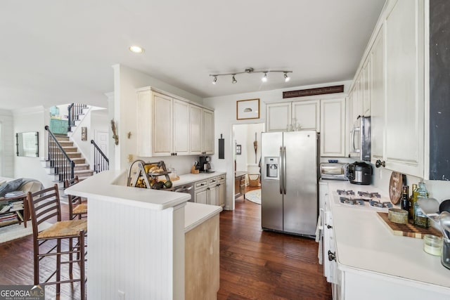 840 Yosemite Dr, Suwanee, GA 30024 - kitchen featuring appliances with stainless steel finishes, a peninsula, dark wood finished floors, a breakfast bar, and light countertops