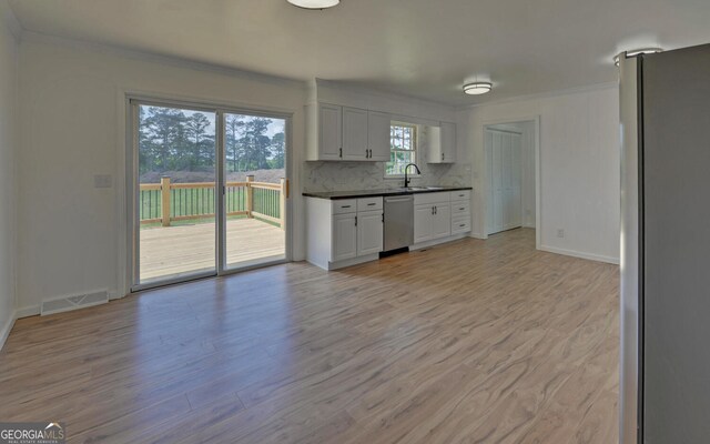 kitchen with appliances with stainless steel finishes, dark countertops, crown molding, tasteful backsplash, and a sink