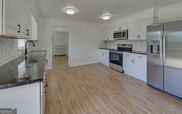 kitchen with stainless steel appliances, a sink, dark countertops, decorative backsplash, and crown molding