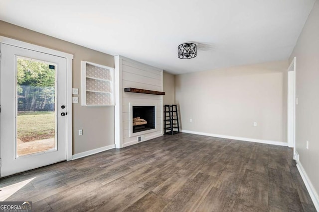 unfurnished living room with wood finished floors, a fireplace, and baseboards