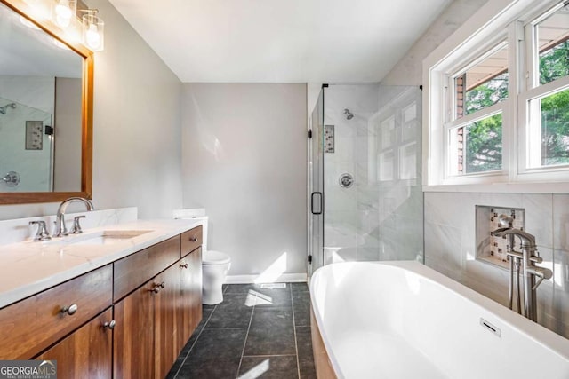 bathroom with a stall shower, vanity, a freestanding tub, baseboards, and tile patterned floors