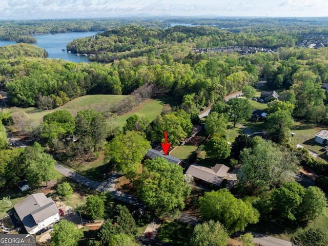 aerial view of property and surrounding area with a heavily wooded area and a nearby body of water