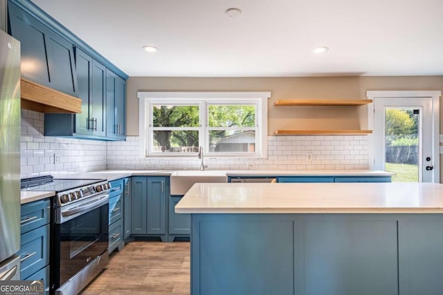 kitchen with appliances with stainless steel finishes, a sink, healthy amount of natural light, blue cabinetry, and recessed lighting