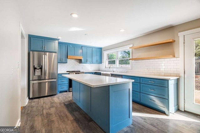 kitchen with stainless steel appliances, blue cabinets, dark wood-style flooring, light countertops, and tasteful backsplash